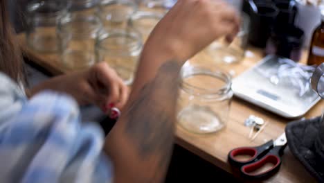 mexican woman with interesting tattoos on her forearm cutting with tweezers thread to make homemade candle wick