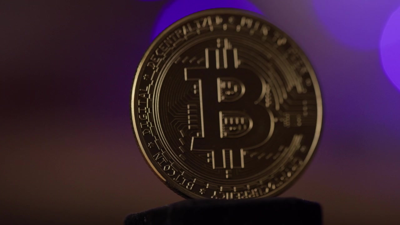 A criptomoeda, bitcoin, girando em direção à luz reflexiva. O futuro do dinheiro. 4K. Bolas de bokeh ao fundo