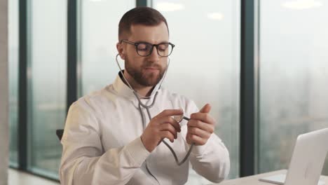 close-up portrait of a male doctor pointing a stethoscope at the camera