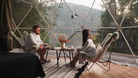 couple enjoying breakfast in a luxury dome house with a scenic view