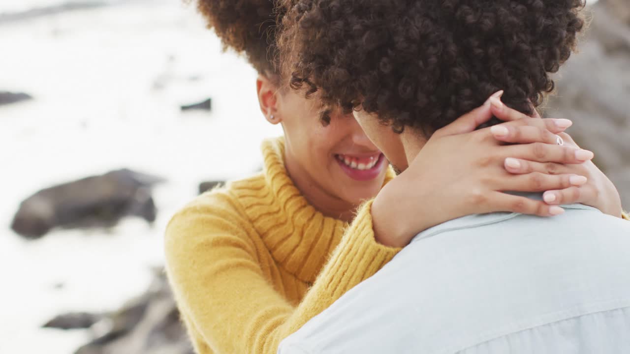 Close up of african american couple embracing each other on the rocks near the sea