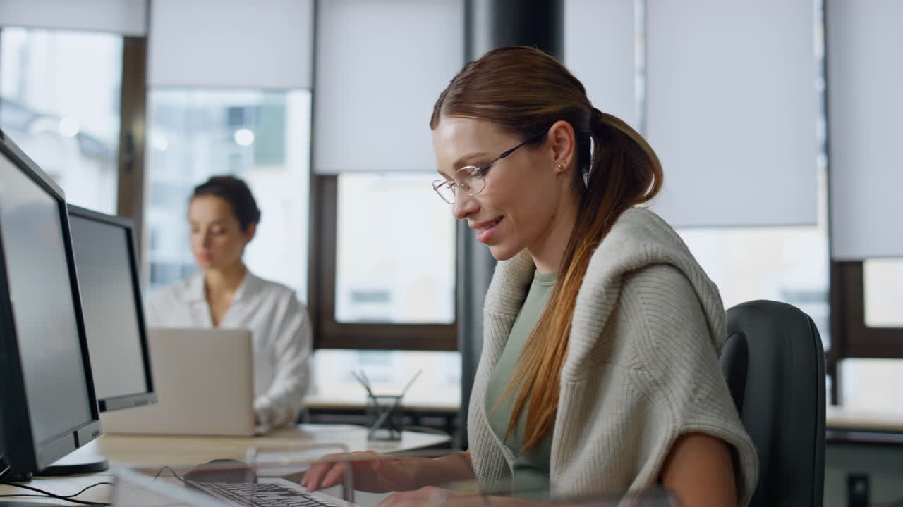 Happy developer typing computer in startup company. Smiling woman coder working