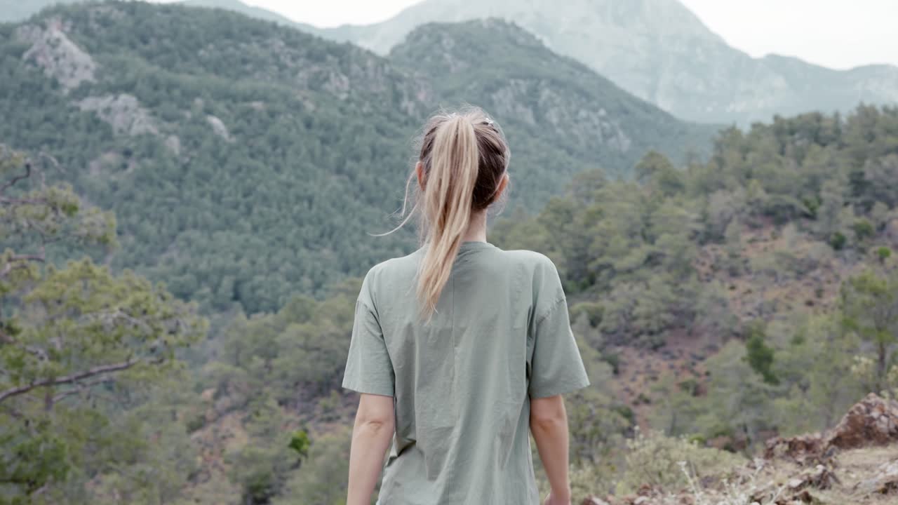 Rear view of a woman alone on the mountain high, enjoying the view