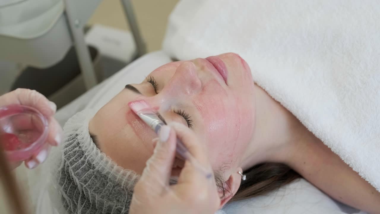 Ansiktspeelingmaske, spa-skjønnhetsbehandling, hudpleie. Kvinne får ansiktspleie av kosmetolog på spa-salong, sidevisning, nærbilde