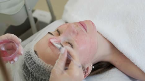 face peeling mask, spa beauty treatment, skincare. woman getting facial care by beautician at spa salon, side view, close-up