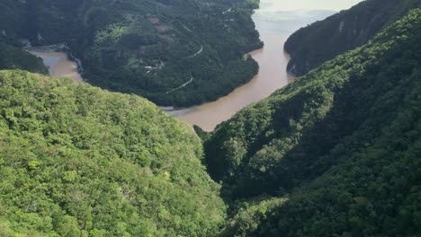 drone flying over lush vegetation with river canyon in background, muchas aguas, san cristobal in dominican republic