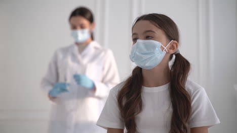 una doctora preparando una vacuna contra el covid-19. una niña con una máscara esperando una inyección para el coronavirus.