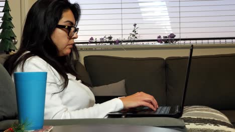 mujer adulta trabajando remotamente desde casa en una cómoda sala de estar usando una computadora portátil