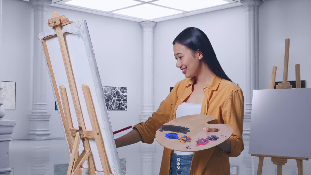 갤러리에서 오일 페인트와 브러쉬로 캔버스에 그림을 그리는 동안 페인트 브러쉬를 사용하여 그림 템플릿을 측정하는 아시아 여성 예술가