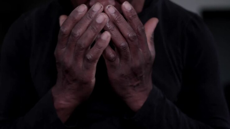 Uomo caraibico che prega Dio con le mani giunte, con sfondo nero - filmato di repertorio