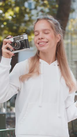 joven turista caucásica mirando el mapa de la ciudad haciendo fotos con una cámara retro vintage