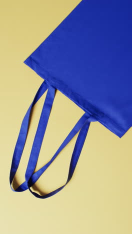 vertical video of blue canvas bag with copy space on yellow background