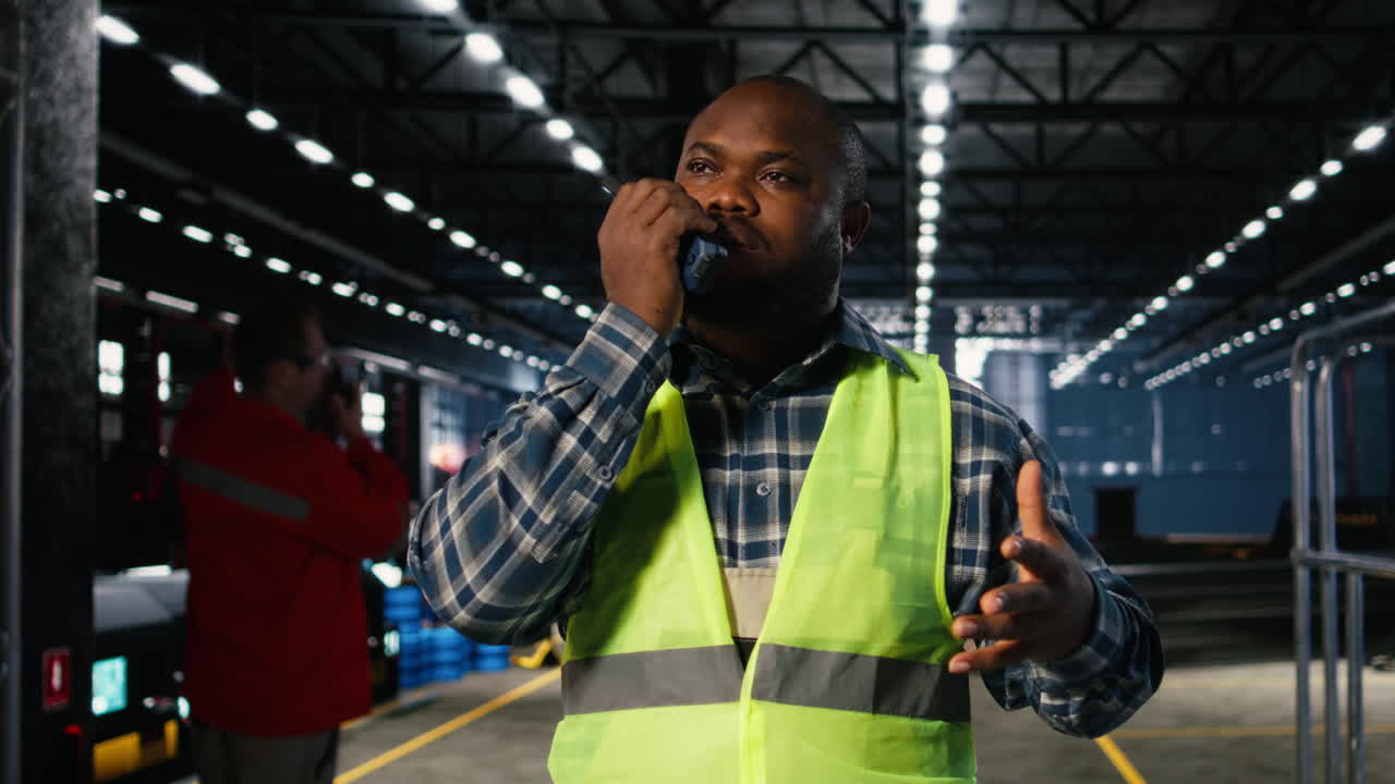 Black engineer talks into walkie talkie and supervising fabrication tools