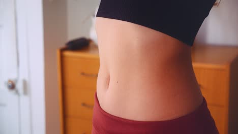 Fit-young-woman-stretching-flat-stomach-inside-apartment