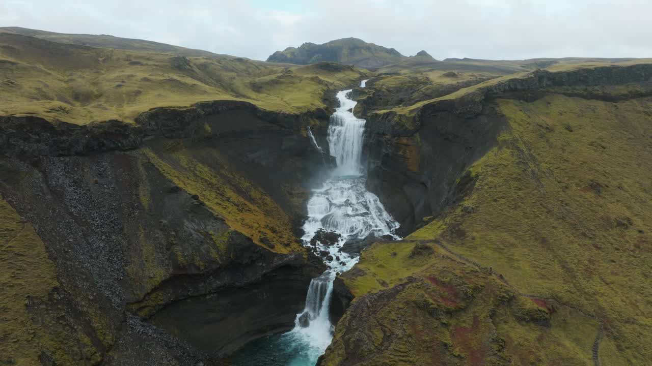 paralaje aéreo alrededor de la cascada ofaerufoss que fluye a través de las tierras altas de islandia