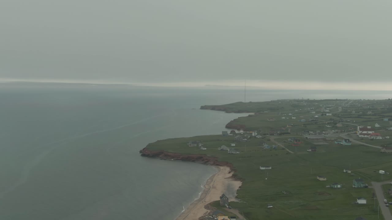 Magnificent View Of Village And Calm Beach By The Lush Green Coastal Plains On Magdalen Islands, Quebec, Canada - aerial drone, panning shot