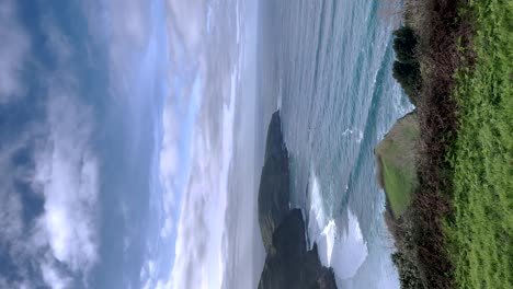 Ocean-waves-in-a-vertical-video,-as-they-gracefully-cascade-onto-the-shores-of-the-Portuguese-Riviera-in-the-Azores,-Portugal,-embodying-the-tranquil-coastal-allure-and-awe-inspiring-natural-beauty