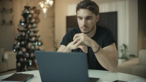 Man-programmer-working-at-laptop-at-new-year-home.-Male-freelance-worker