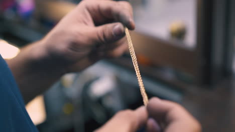 jeweler holds golden bracelet in light workshop close view