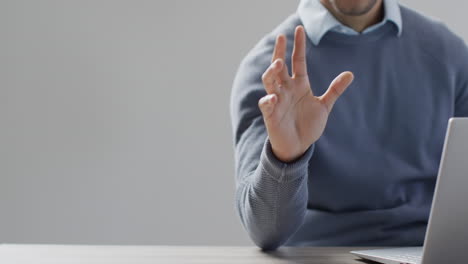 sección media de un hombre de negocios biracial usando una computadora portátil y una pantalla holográfica, con espacio para copiar