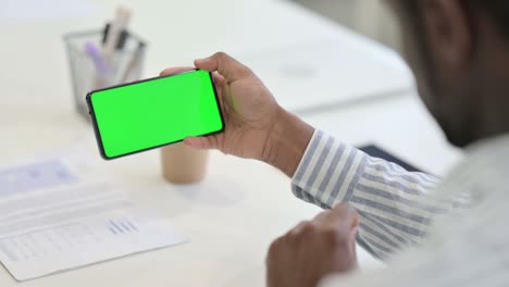 rear view of african man looking at smartphone with green chroma key screen