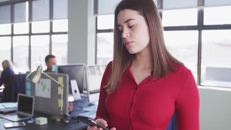 Businesswoman-using-smartphone-in-modern-office