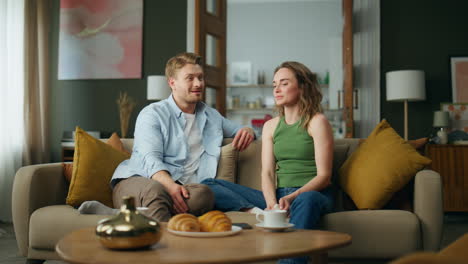 loving couple relaxing sofa together home weekend. smiling woman talking to man