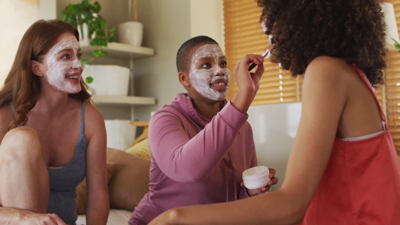Gruppo eterogeneo di amiche felici che provano il trucco e parlano a casa.
