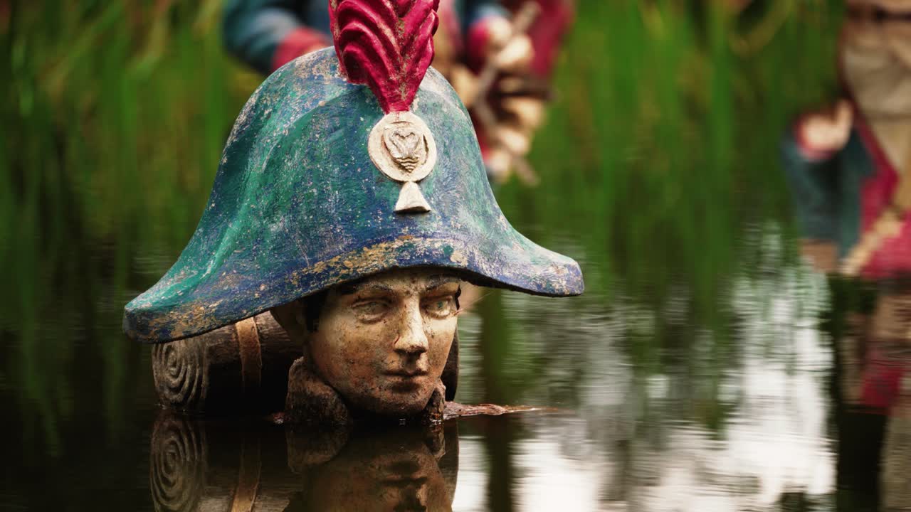 Decaying Napoleon statue in water pond in abandoned theme park, close up