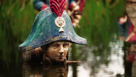 Decaying-Napoleon-statue-in-water-pond-in-abandoned-theme-park,-close-up