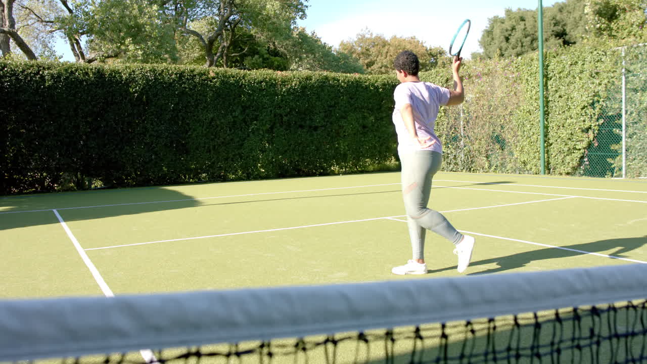 Playing tennis, woman hitting ball on outdoor court, enjoying sunny day