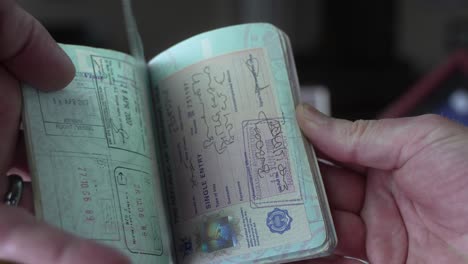 hombre sostiene su pasaporte estadounidense lleno de visados de viaje extranjeros - hojeando páginas