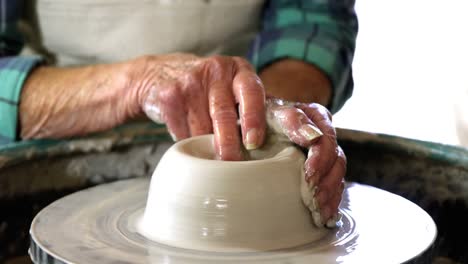 Mid-section-of-female-potter-making-pot