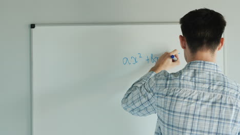 student writes on equation board