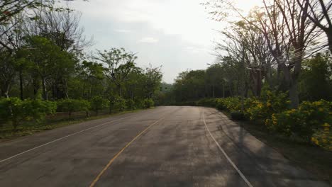 An-aerial-drone-footage-going-forward-chasing-the-pavement-of-a-road-at-a-village-in-Muak-Klek,-Thailand