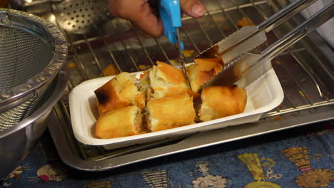 person cutting and serving spring rolls to costumer