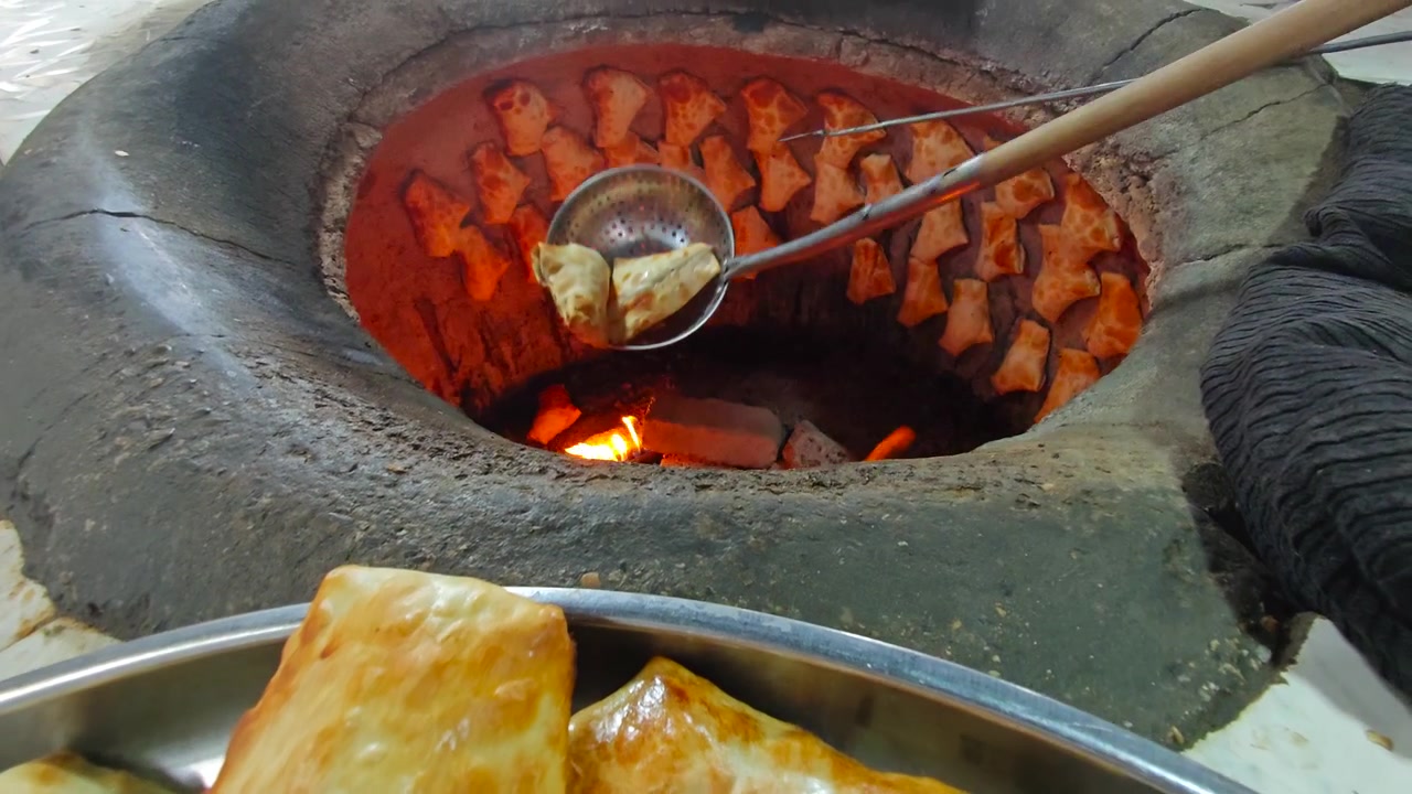 Người thợ làm bánh lấy bánh Samsa mới nướng ra khỏi lò Tandoor truyền thống