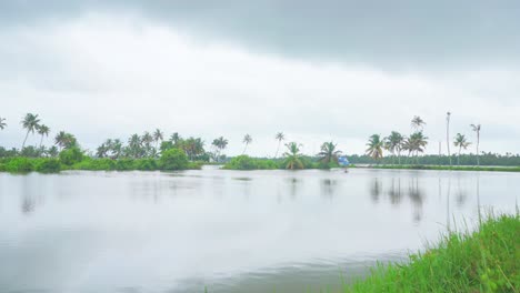 A-large-lake-is-dammed-for-fish-farming-,-Flooding-has-occurred-due-to-rain-,-coconut-grove,-the-walkway-and-the-dark-sky-,panning-shot