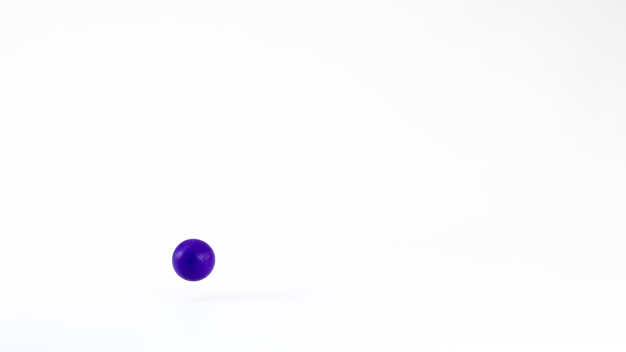 A solid blue sphere bounces and rolls across a clean white studio floor in slow-motion