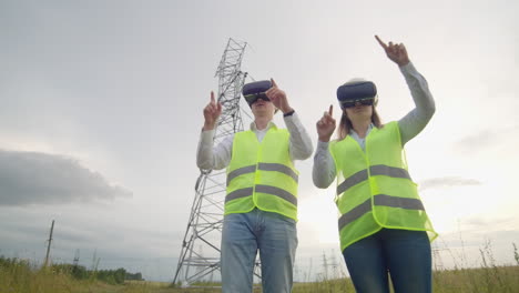 un hombre y una mujer ingenieros en gafas vr controlan la distribución de energía de las redes eléctricas y la entrega de electricidad contra el fondo de torres eléctricas con cables de alto voltaje