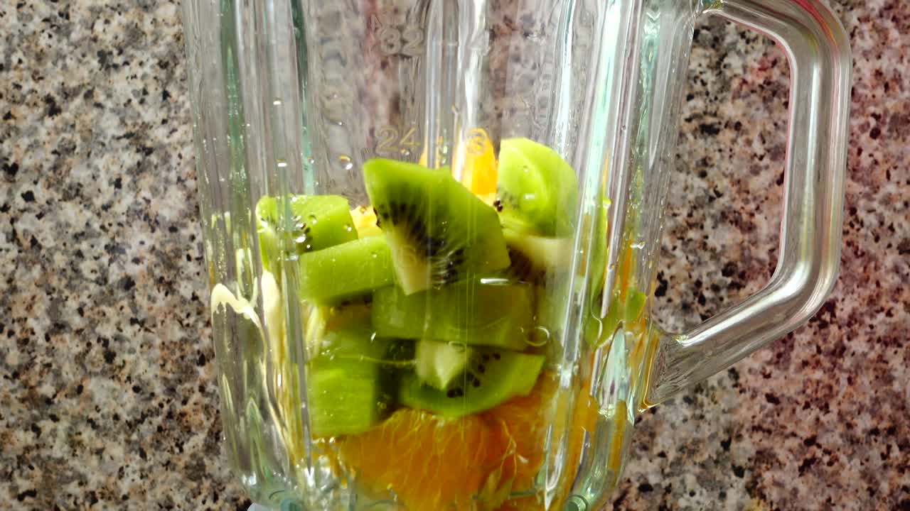Riempimento del frullatore con kiwi, arance e banane