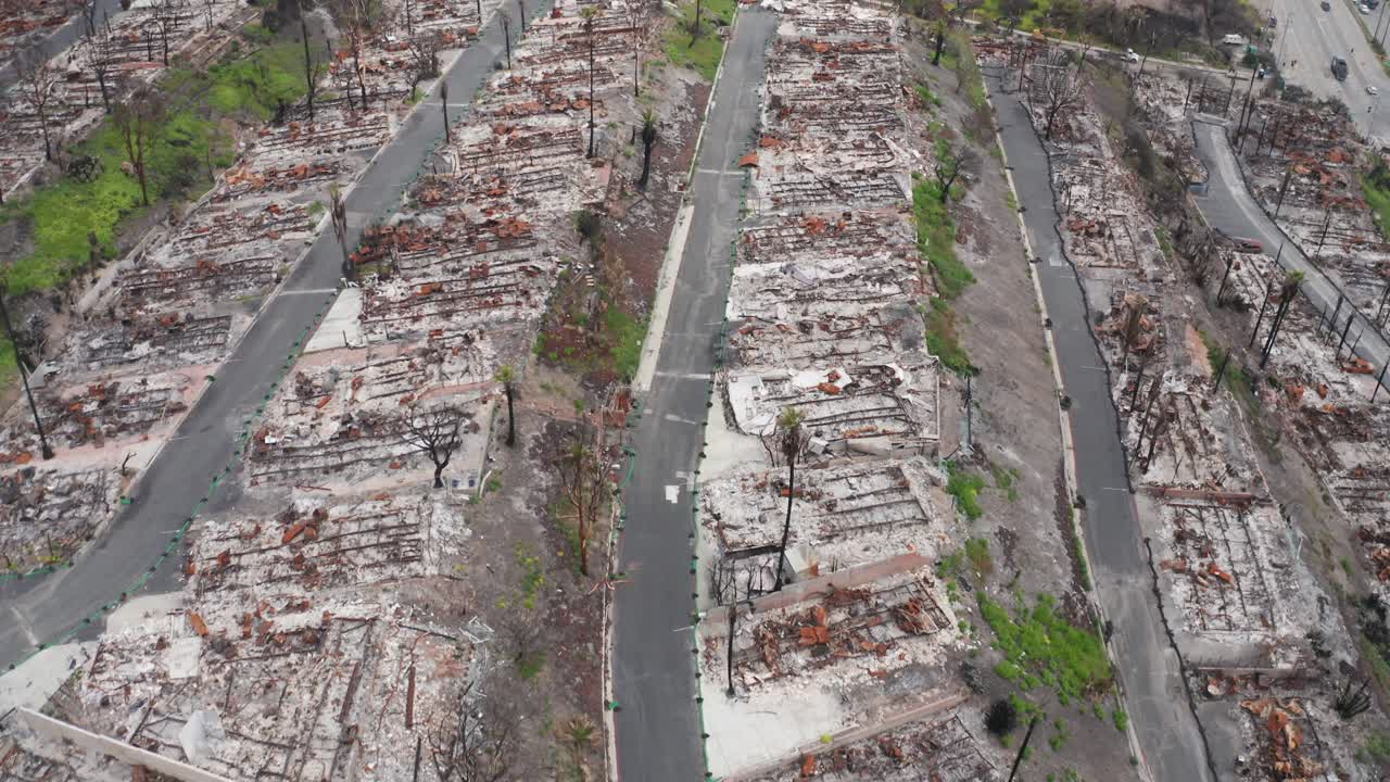 Aerial low bird's eye shot flying over a scorched oceanfront mobile home community in Pacific Palisades after the wildfires in Los Angeles, California. 4K
