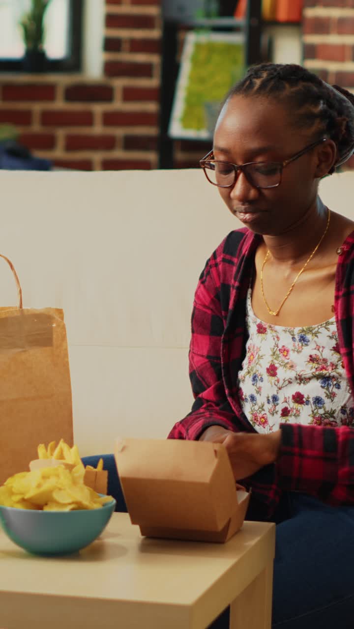 Vertical video: Happy woman eating hamburgers with fries and beer,