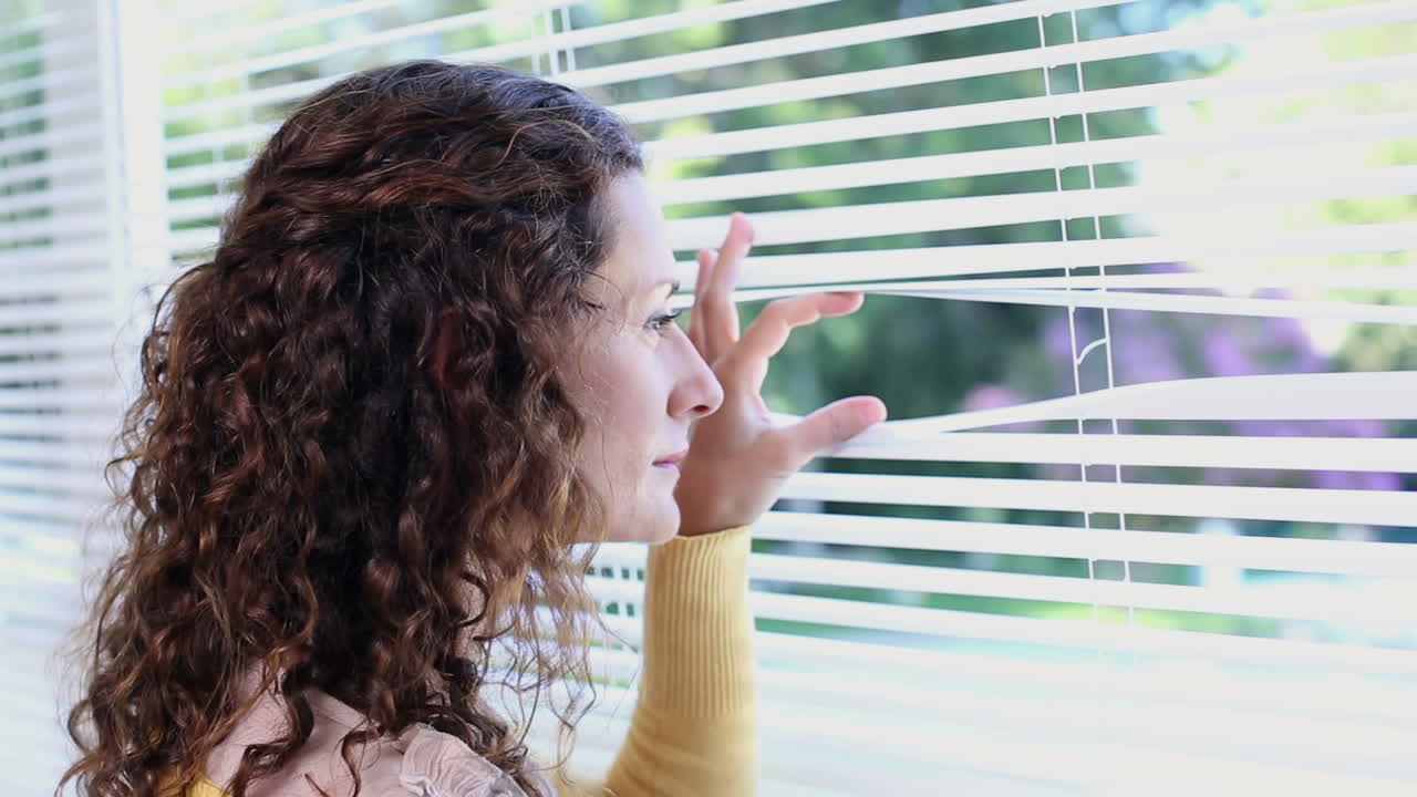 Woman peeking through blinds