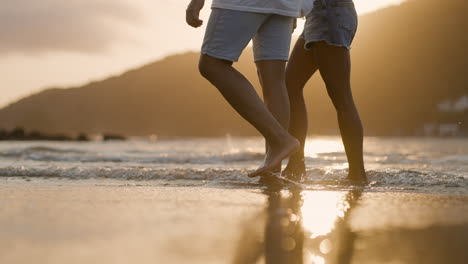 un couple se tenant par la main au coucher du soleil.