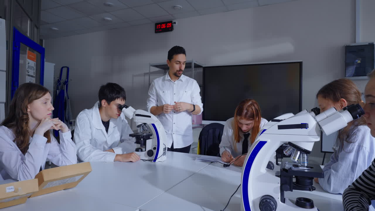 los estudiantes en una clase de ciencias usan microscopios durante una lección