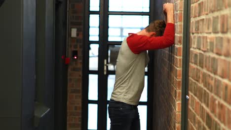 tired businessman leaning on wall