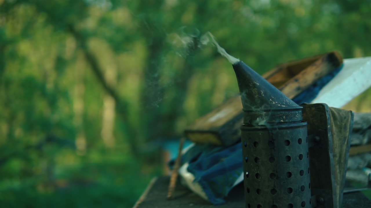 Black Bee Smoker Resting On Beehive With Smoke Coming Out Of Nozzle. Locked Off