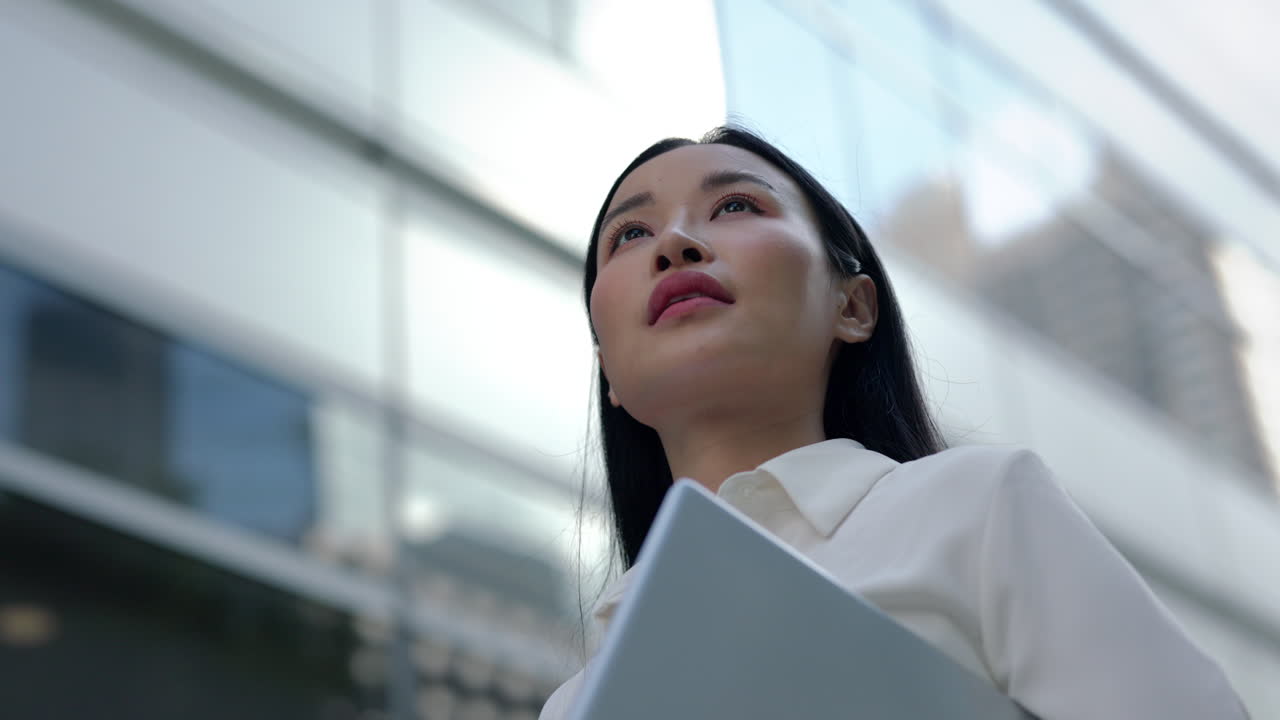 Confident Asian Businesswoman Looking Up in Urban Setting