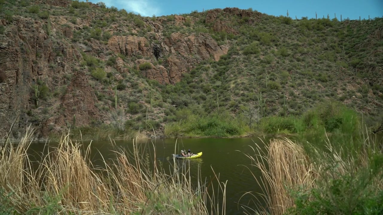 Canyon Lake, Apache Junction, Arizona. Sitio Recreativo Boulder. Un kayak inflable para dos personas en aguas tranquilas con un desierto, colina, rocas y cactus saguaro al fondo